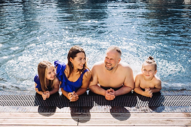 Familia feliz con dos niños divirtiéndose en la piscina Concepto de vacaciones de verano