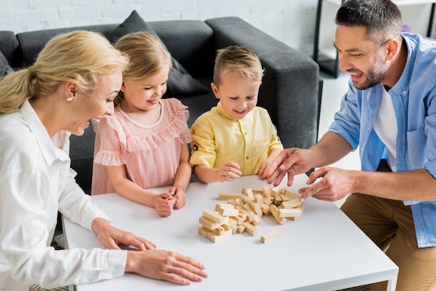 familia feliz con dos niños jugando con bloques de madera en casa