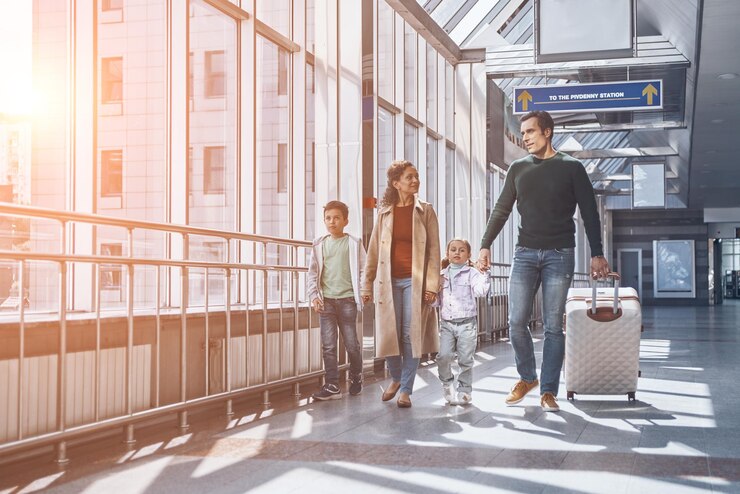 Familia feliz con dos niños pequeños caminando por la terminal del aeropuerto