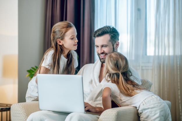 Família feliz. duas garotas mostrando seu amor ao pai e parecendo felizes