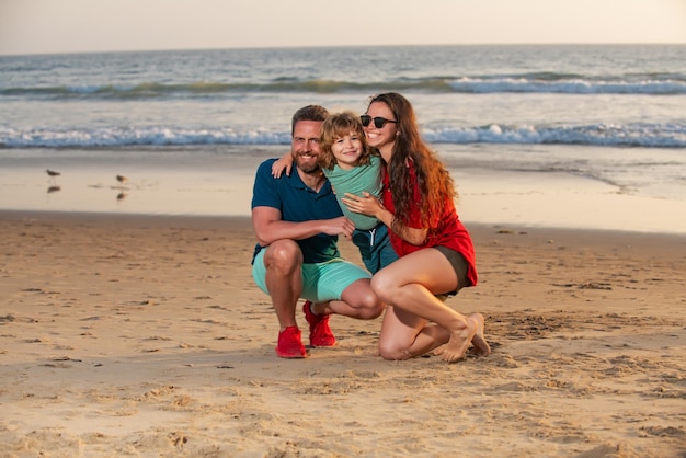 Família feliz e criança desfrutando do pôr do sol na praia Lazer de verão