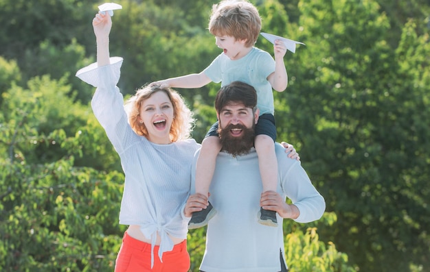 Família feliz e filho pequeno brincando no céu azul de verão pai mãe e filho no parque família feliz