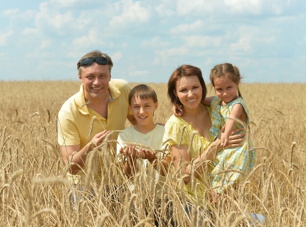 Família feliz e sorridente em pé no campo de trigo