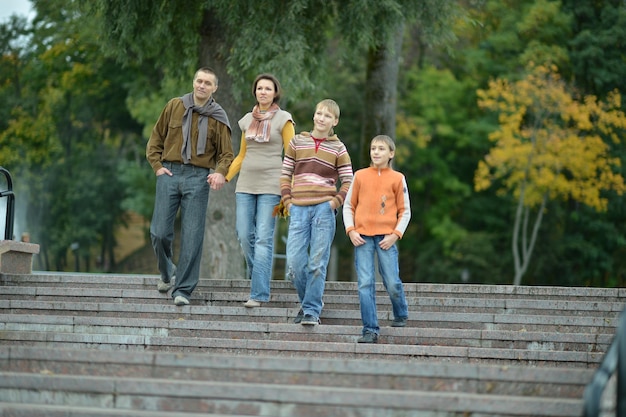 Família feliz e sorridente na floresta de outono andando