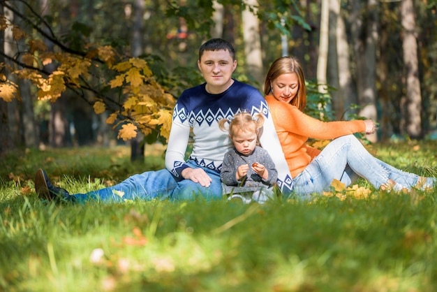 Família feliz e sorridente relaxando no parque outono
