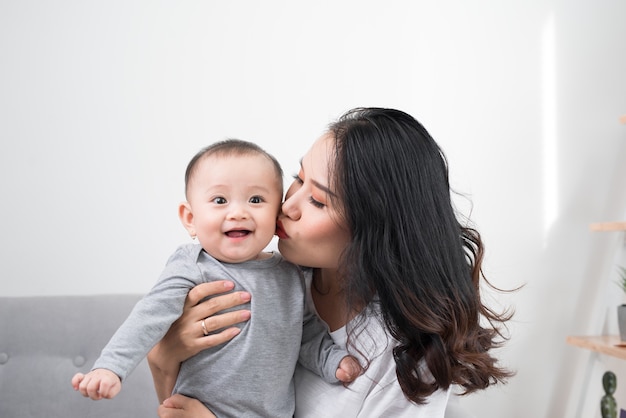 Família feliz em casa. mãe segurando filha bebê na sala de estar na manhã aconchegante de fim de semana