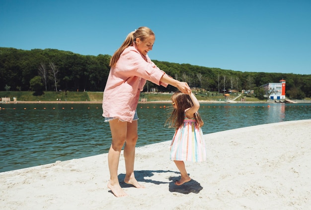 Família feliz em férias na praia Mãe e filha estão andando e brincando na praia Mãe e bebê se divertem na praia