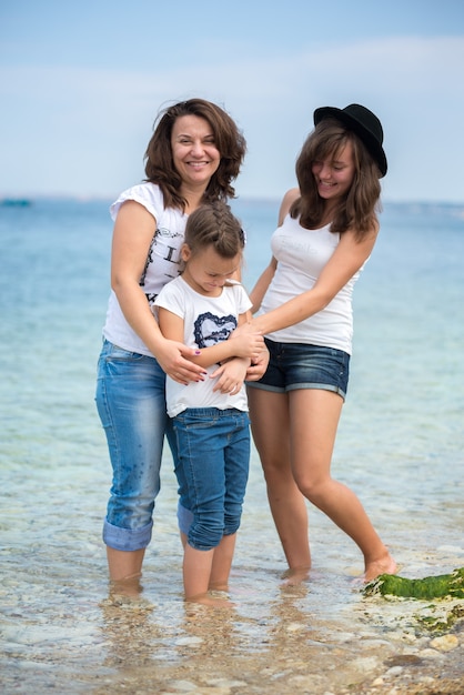 Família feliz em pé em um pontão de madeira em frente ao mar no verão