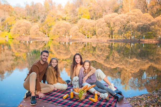 Família feliz em um piquenique no parque no outono