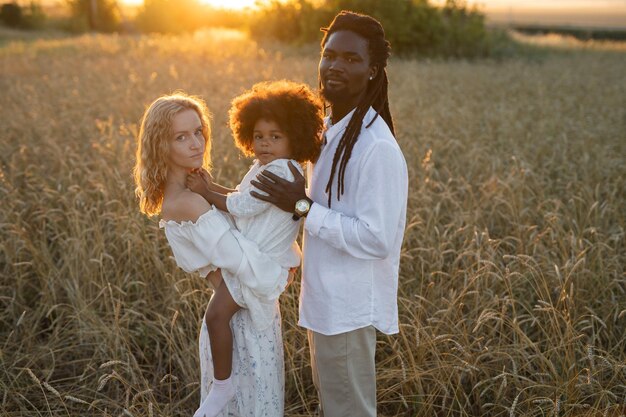 Foto família feliz em uma caminhada em um campo de verão ao pôr do sol