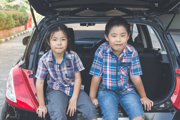 Família feliz em uma viagem, sentado no tronco do carro