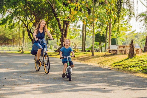 Família feliz está andando de bicicleta ao ar livre e sorrindo. A mãe de bicicleta e o filho de bicicleta.