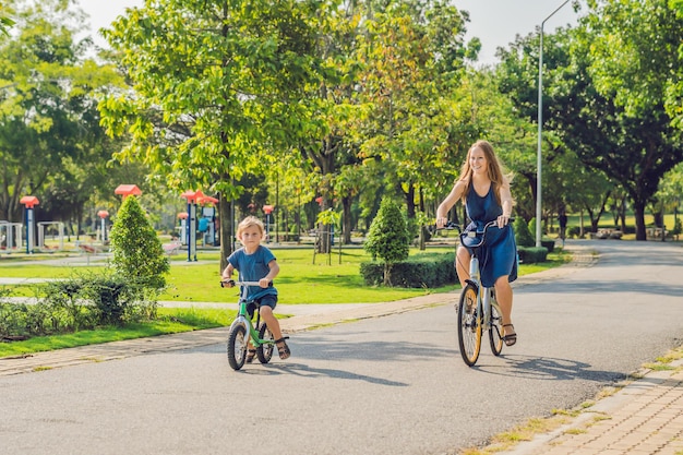 Família feliz está andando de bicicleta ao ar livre e sorrindo. Mãe em uma bicicleta e filho em uma bicicleta equilibrada