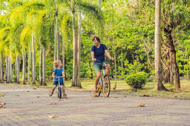 Família feliz está andando de bicicleta ao ar livre e sorrindo. Pai em uma bicicleta e filho em uma balancebike