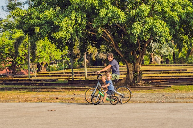 Família feliz está andando de bicicleta ao ar livre e sorrindo. Pai em uma bicicleta e filho em uma balancebike