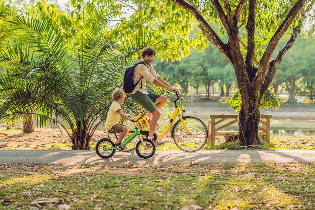 Família feliz está andando de bicicleta ao ar livre e sorrindo. Pai em uma bicicleta e filho em uma balancebike