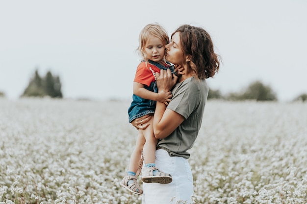 Familia feliz está jugando, divirtiéndose en el campo con flores al atardecer.