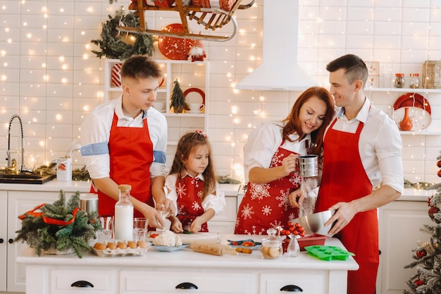 Una familia feliz está de pie en la cocina de Navidad y prepara la masa para hacer galletas.