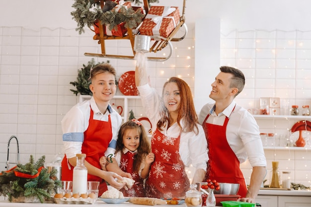 Una familia feliz está de pie en la cocina de Navidad y prepara la masa para hacer galletas.