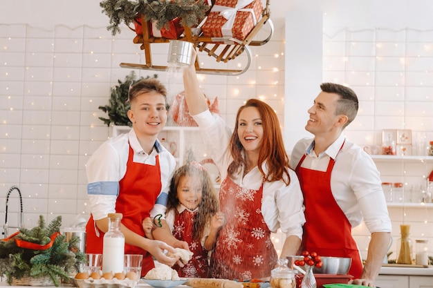 Una familia feliz está de pie en la cocina de Navidad y prepara la masa para hacer galletas.