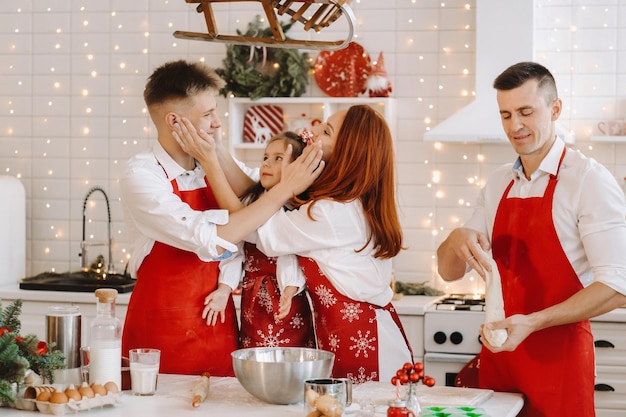 Una familia feliz está de pie en la cocina navideña y se unta con harina.