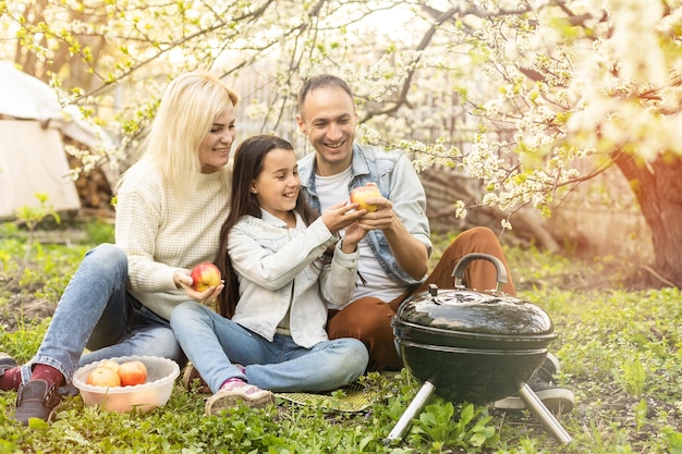 Família feliz fazendo churrasco com churrasqueira moderna ao ar livre.