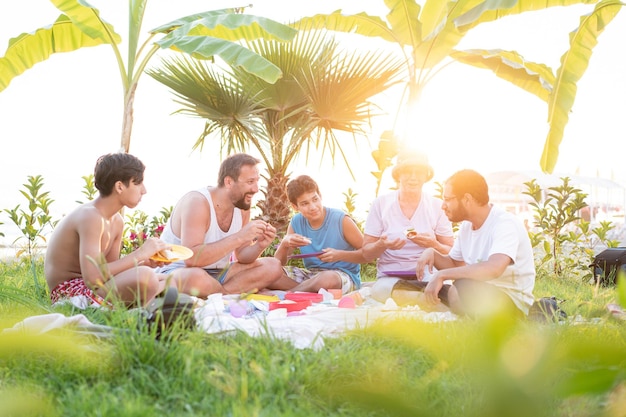 Família feliz fazendo piquenique na praia perto do mar