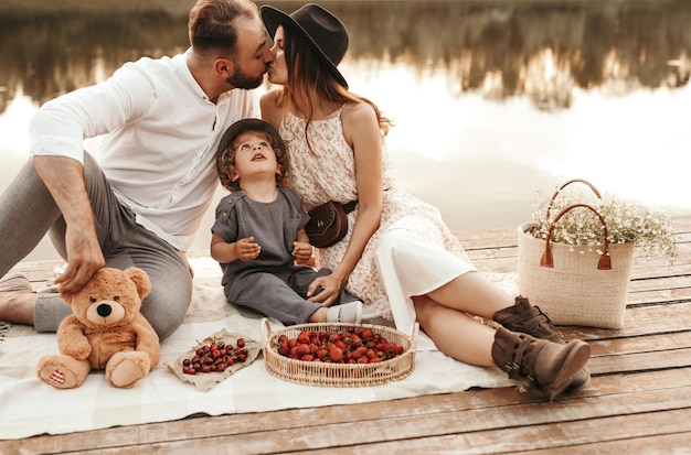 Família feliz fazendo piquenique no cais perto do lago