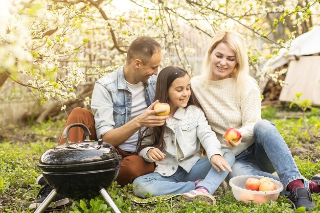 Família feliz fazendo um churrasco em seu jardim na primavera. Conceito de lazer, comida, família e férias.