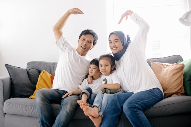 Familia feliz formando amor o corazón con sus manos en casa