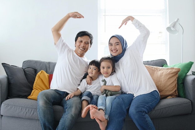 Família feliz formando amor ou coração com as mãos em casa