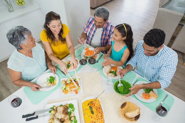 Família feliz geração multi, tendo a refeição na mesa em casa