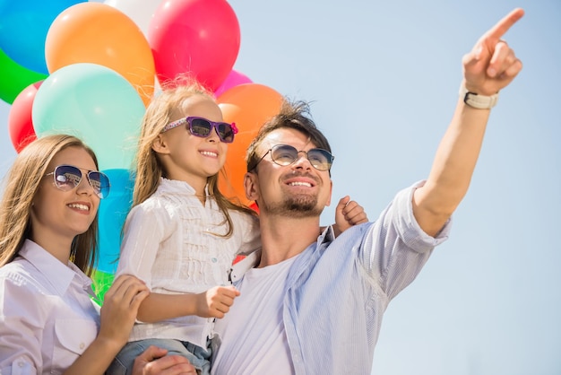 Familia feliz con globos mirando hacia arriba al aire libre en un día de verano.