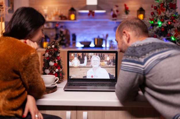 Familia feliz hablando con la abuela remota durante la reunión de videollamada en línea