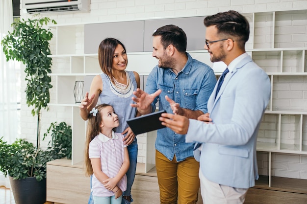 Familia feliz hablando con un agente inmobiliario sobre la compra de una nueva casa.