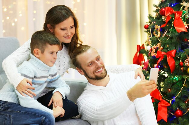 Familia feliz haciendo fotos en la sala de estar de vacaciones en casa