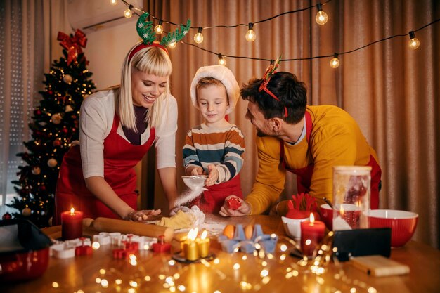 Familia feliz haciendo galletas de pan de jengibre juntos en casa en Navidad