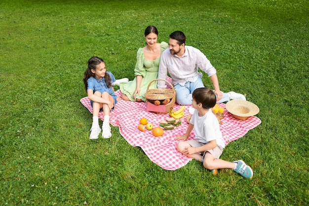 Familia feliz haciendo picnic juntos en el parque