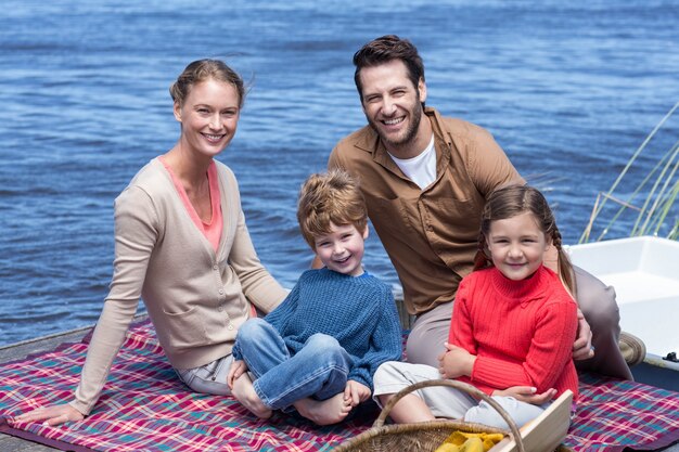 Familia feliz haciendo picnic en un lago