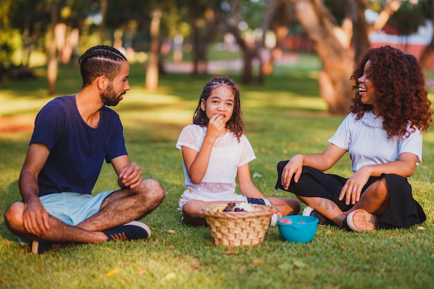 Familia feliz haciendo picnic en el parque