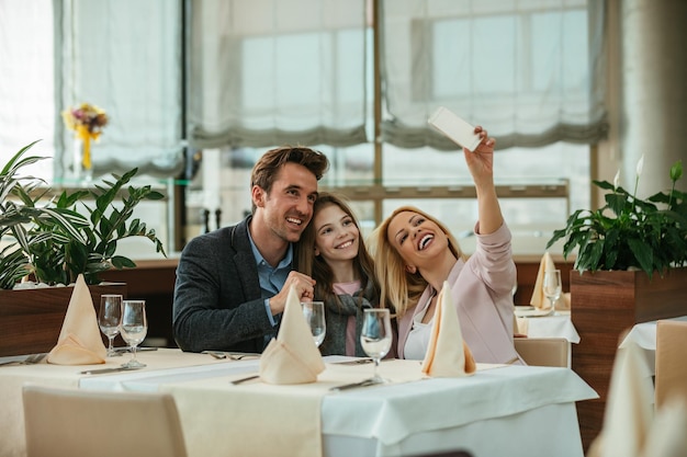 Familia feliz haciéndose un selfie en un restaurante