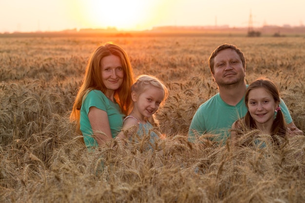 Familia feliz con hijas en el campo de trigo