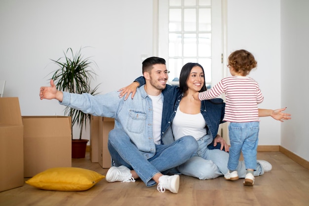 Familia feliz con un hijo pequeño divirtiéndose en un nuevo hogar después de mudarse