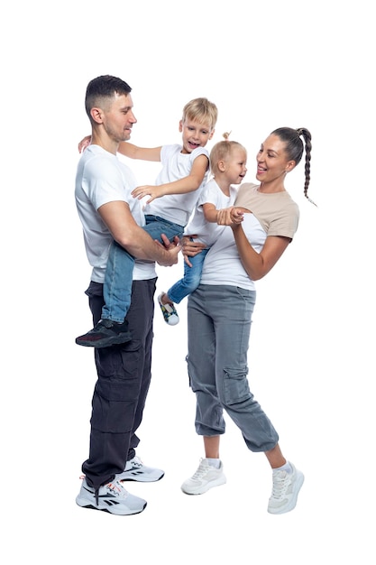 Familia feliz con hijos madre padre hija e hijo en camisetas y vaqueros blancos abrazarse y reírse amor y ternura altura completa aislado sobre un fondo blanco vertical