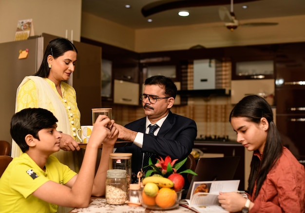 família feliz, hora do chá, sentado na mesa de jantar modelo indiano do paquistanês