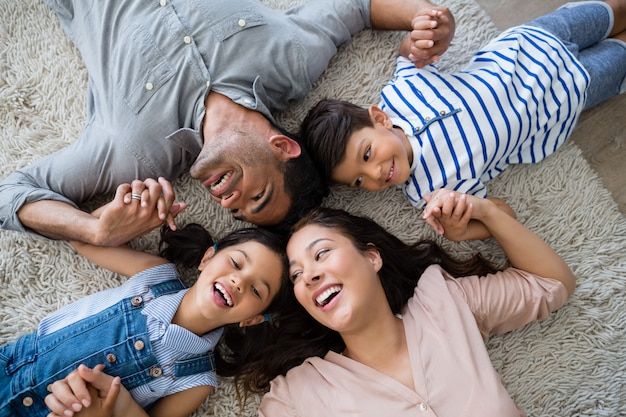 Familia feliz interactuando mientras está acostado en la alfombra