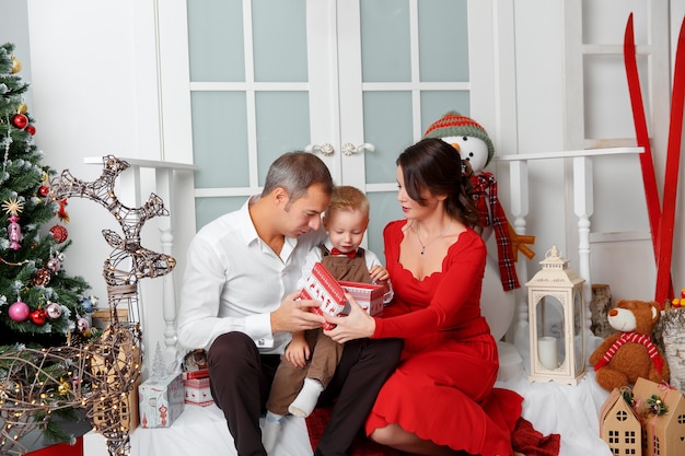 Familia feliz en el interior de la casa en el fondo del árbol de Navidad con regalos. Vacaciones de año nuevo.