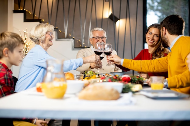 Família feliz jantando com vinho tinto em casa