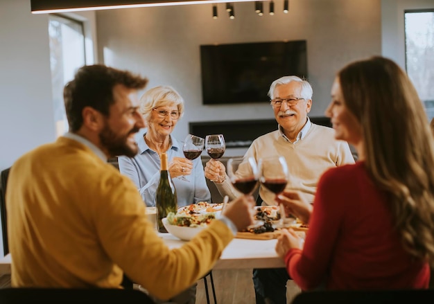 Família feliz jantando com vinho tinto em casa