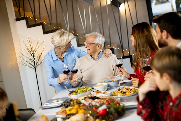 Família feliz jantando com vinho tinto em casa